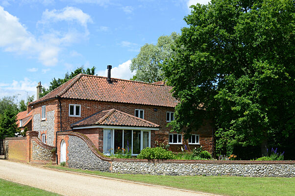 Red brick home with conservatory behind a flint wall
