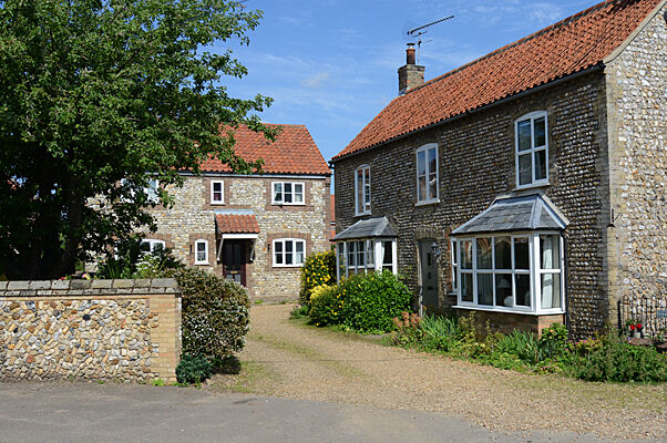 Flint cottage-style home with bay window