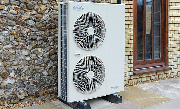 Air source heat pump fitted against a flint wall