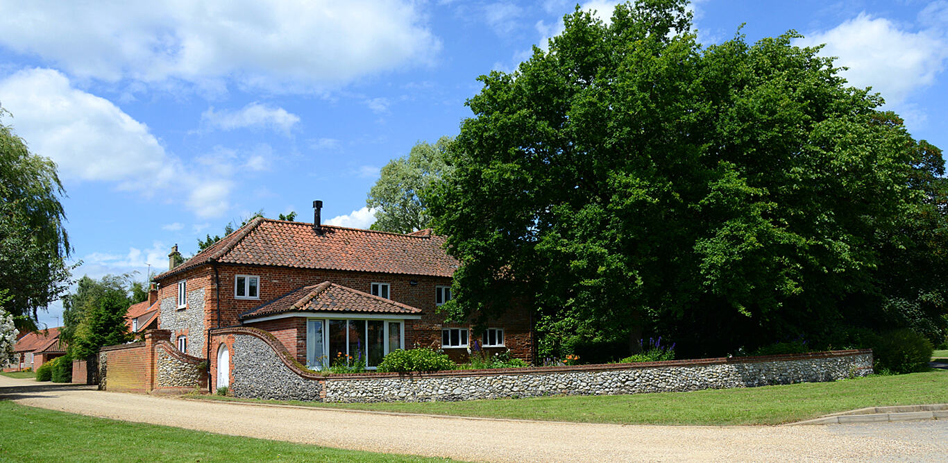 Red brick home set behind a flint wall